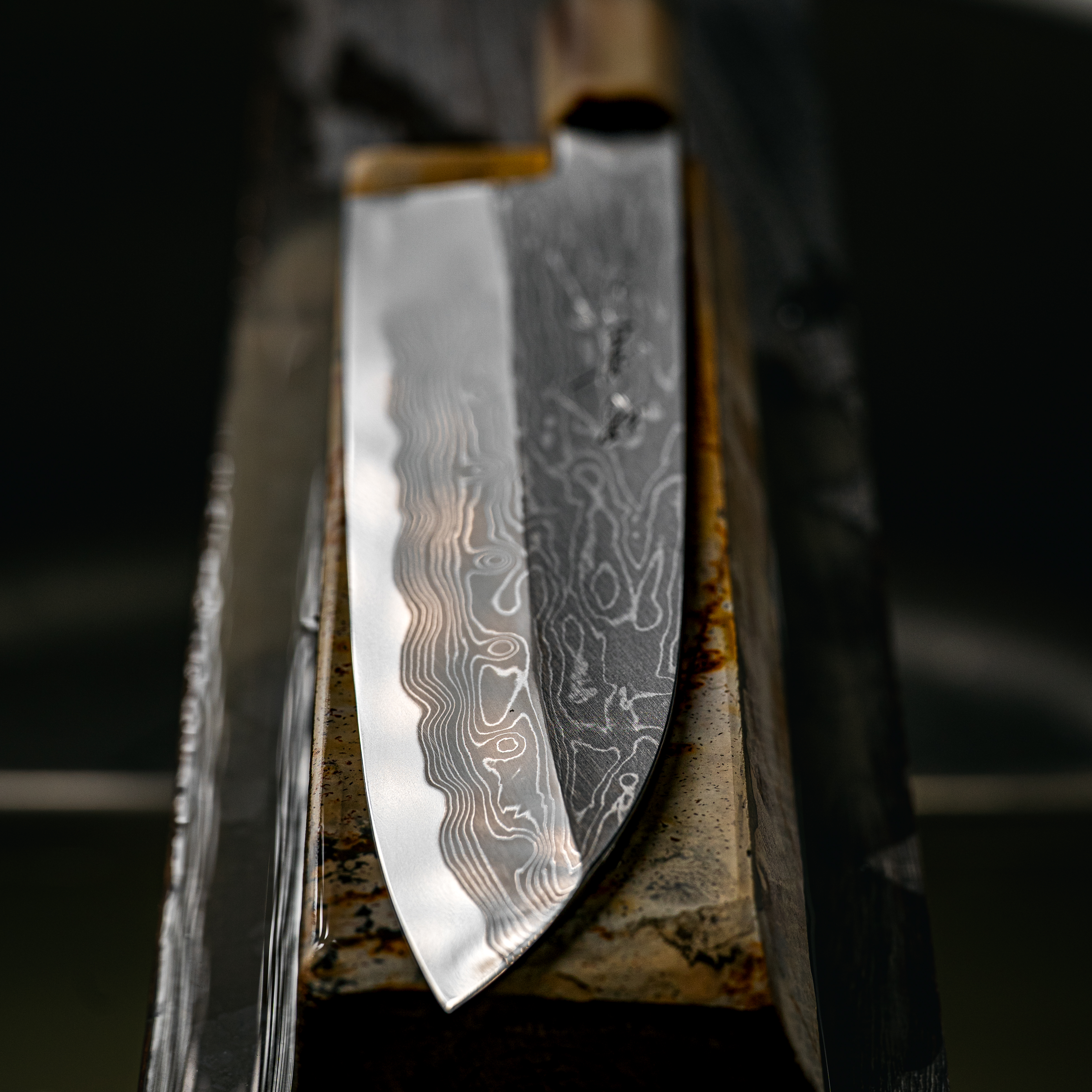 A patterned knife blade resting on a whetstone